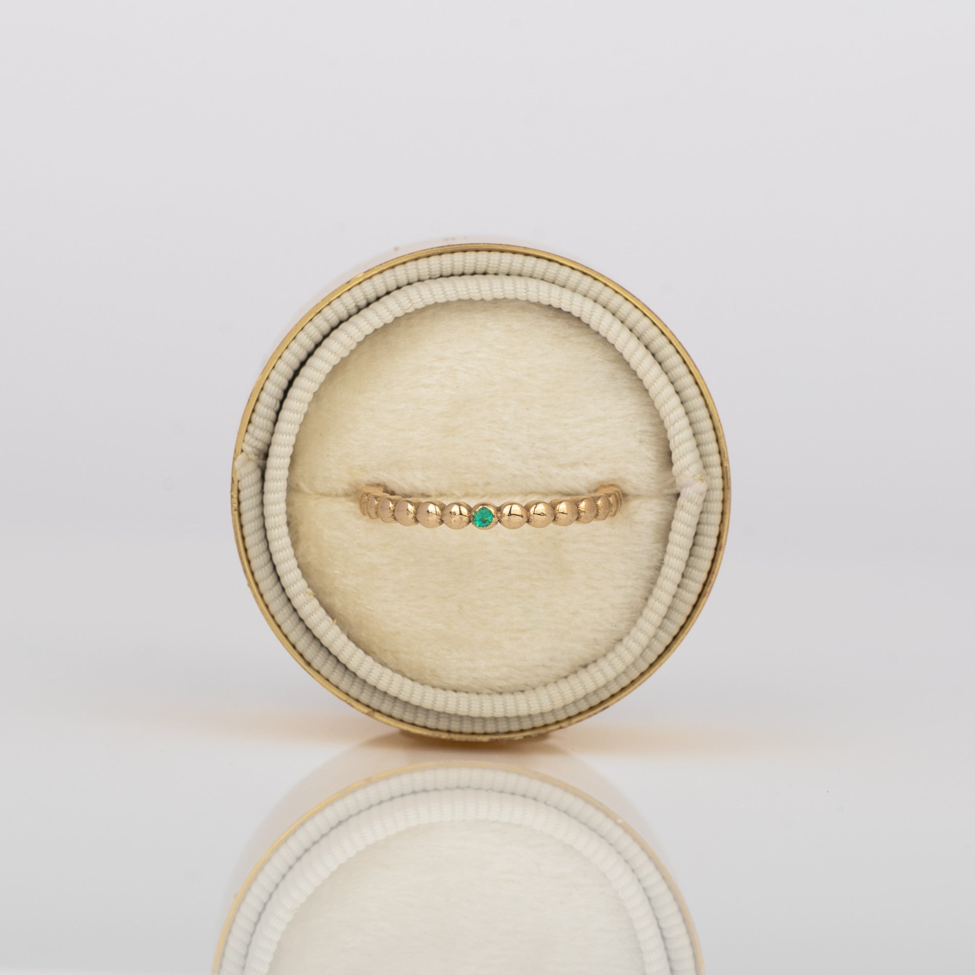 all-groups close up on beaded 14k gold ring with emerald in velvet box