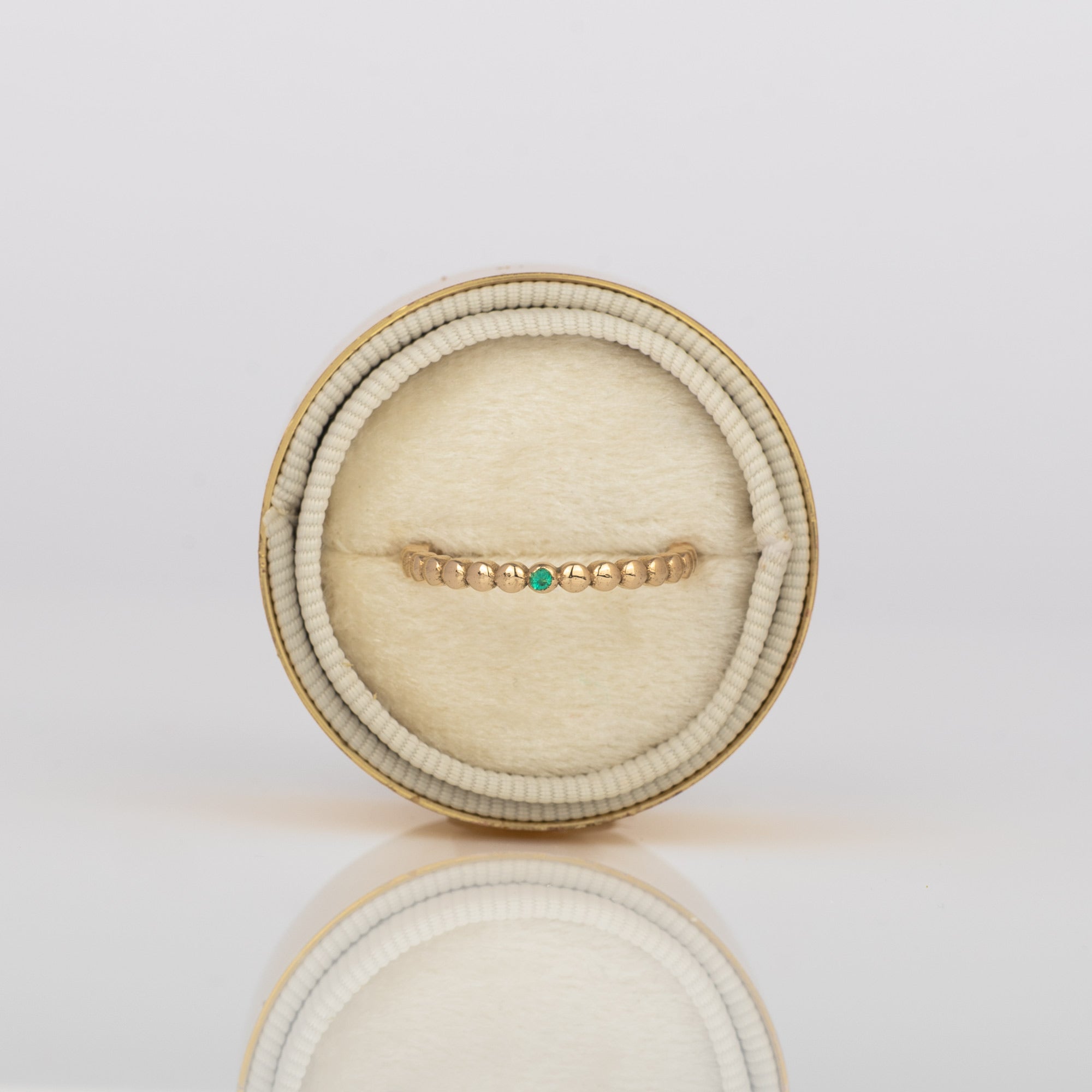 close up on beaded 14k gold ring with emerald in velvet box